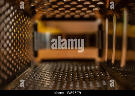 Vue depuis l'intérieur de la cuisine grater. La texture d'une surface métallique avec des trous. Focus sélectif. Banque D'Images