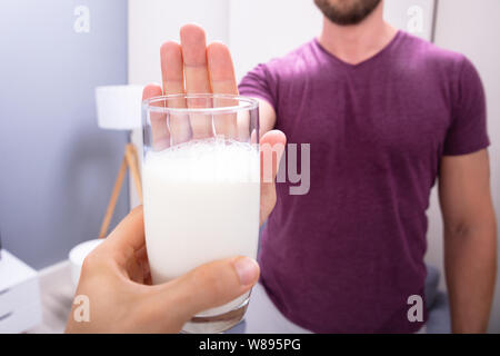 Portrait d'un homme rejetant Verre de lait offert par personne à la maison Banque D'Images