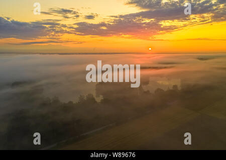 Matin brouillard sur un lac alors que le soleil se lève. Banque D'Images