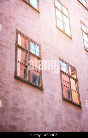 Une partie de la façade d'un bâtiment historique rouge allumé, qui se reflète sur des vitres, dans la vieille ville de Gamla Stan, Stockholm, Suède. Série - stre Banque D'Images