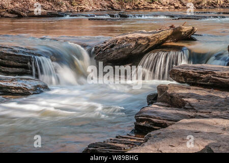 Petites chutes d'eau tumbling sur les rochers en aval dans une rivière sur une journée ensoleillée en hiver jusqu'fermer Banque D'Images