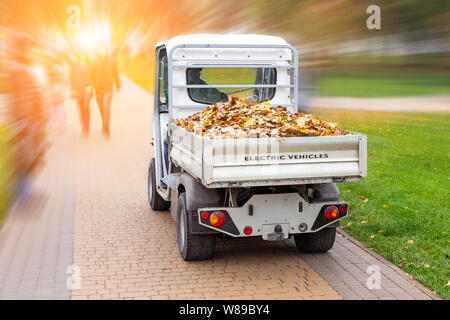 Petit chariot électrique suppression de feuilles tombées dans l'administration à l'automne parc de la ville. Les services urbains municipaux à l'aide de camion véhicule vert de l'écologie à la propreté des rues Banque D'Images