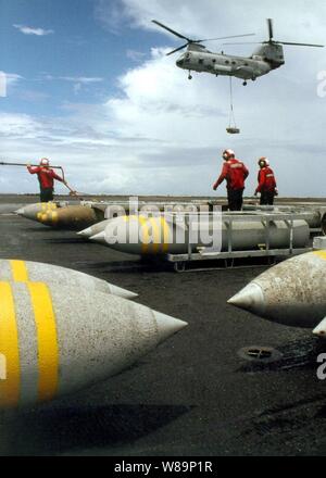 Une Marine CH-46 Sea Knight helicopter offre une autre palette de bombes à l'envol de l'USS John F. Kennedy (CV 67) au cours d'une évolution des munitions avec l'USNS onload Mount Baker (T-AE 34) que les navires opèrent dans l'Océan Atlantique le 22 juillet 2001. Red-shirted ordnancemen l'aviation se déplace les palettes de bombes au poste de pilotage à l'shipХs magazines sous le pont pour le stockage. Banque D'Images