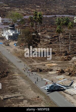 Citoyens indonésiens courir vers un Marine américain SH-60 Seahawk hélicoptère transportant de la nourriture et autres fournitures de secours à Sumatra, Indonésie, le 7 janvier 2005. Porte-hélicoptères affectés à l'aile Deux Air 2 et les marins de l'USS ABRAHAM LINCOLN (CVN 72) mènent des opérations humanitaires dans le sillage de la 26 décembre 2004, du tsunami qui a frappé l'Océan Indien. Le Lincoln est opérant dans l'Océan Indien au large des côtes de l'Indonésie et la Thaïlande dans le cadre de l'opération Unified Assistance. Banque D'Images