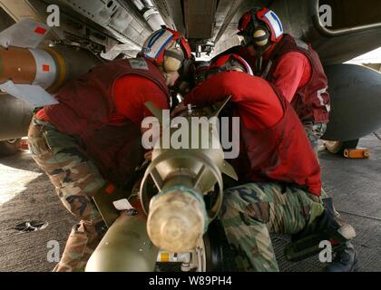 Ordnancemen Aviation Marine travaillent ensemble pour monter des bombes guidées au laser sous un F-14B Tomcat au cours de la lutte contre les préparatifs sur le pont d'envol du porte-avions USS Harry S. Truman (CVN 75) le 1 er février 2005. Les avions de l'Escadre aérienne de transporteur 3 est lancé sur le Truman fournissent l'appui aérien rapproché et la réalisation d'intelligence, de missions de surveillance et de reconnaissance au cours d'opérations dans le golfe Persique. Banque D'Images