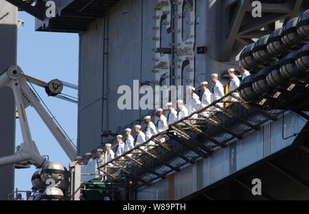 Les marins de la Marine américaine à bord du porte-avions USS Nimitz (CVN 68) les rails que le navire quitte le quai à Naval Air Station North Island à San Diego, Californie, le 7 mai 2005, pour un déploiement de six mois à l'ouest du Pacifique à l'appui de la guerre contre le terrorisme. Banque D'Images