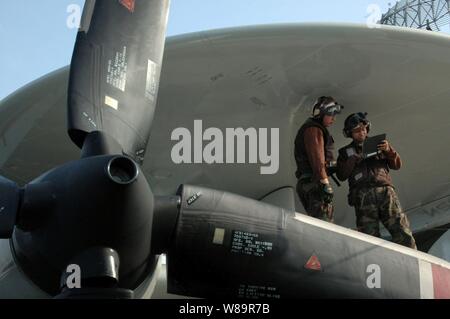 Le Capitaine aviateur avion Nathaniel riche (à droite) et d'un membre de Ricardo Sawh banc sous l'abri du radar rotodome aussi riche indique à son stagiaire Sawh comment effectuer une inspection quotidienne sur un E-2C Hawkeye sur le pont de l'USS Kitty Hawk (CV 63) le 7 novembre 2005. Le Hawkeye est affecté à l'Escadron aéroporté de détection lointaine de l'opérateur 115. Banque D'Images