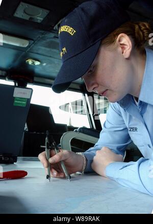 Le Maître de 3e classe de la marine Sarah Eléazar trace la position de l'USS Theodore Roosevelt (CVN 71) sur un graphique dans l'équipage du navire la passerelle de navigation, le 16 décembre 2005. Roosevelt et son escadre aérienne de transporteur 8 mènent des opérations de sécurité maritime dans le golfe Persique. Eléazar est un quartier-maître de la marine à bord du porte-avions. Banque D'Images