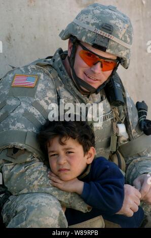 Un garçon irakien repose sur le bras de l'armée américaine le Cpl. James Reinhard à l'extérieur d'un ministère de la police irakienne à Bagdad, l'Iraq, le 12 mars 2006. Reinhard et autres soldats du 519e Bataillon de la police militaire sont des uniformes de policiers et d'autres engins de la police à la police irakienne à la gare. Banque D'Images