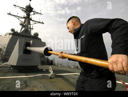 Le Maître de 2e classe de la Marine Michael West nettoie le canon d'un MK-45 5 pouces, 54 armes de gros calibre sur la proue du destroyer lance-missiles USS Shoup (DDG-86) comme le navire opère dans la mer de Chine du Sud, le 18 avril 2006. West est un gunnerís Marine mate à bord du navire de la classe Arleigh Burke. Banque D'Images