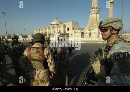 La 1ère Armée américaine Sgt. Dan L. Schoemaker permet de sécuriser la rue à l'extérieur d'une mosquée dans l'annonce Hamyah district de Bagdad, Irak, soldats de l'armée irakienne, à partir de la 9e armée iraquienne peut rechercher pour munitions le 2 septembre 2006. Schoemaker est affecté à la Compagnie Charlie, 1er Bataillon, 17e Régiment d'infanterie, 172e Stryker Brigade Combat Team. Banque D'Images