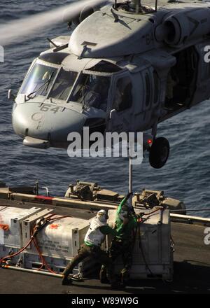 Les marins de la Marine américaine à bord du porte-avions à propulsion nucléaire USS Enterprise (CVN 65) Branchez le cargo au ventre d'un hélicoptère Seahawk MH-60S au cours d'un ravitaillement en mer avec le transport maritime militaire rapide Commande de navire de soutien au combat (T'offre l'USNS-AOE 6) pendant qu'ils sont en cours dans le golfe Persique sur 28 Octobre, 2007. Banque D'Images