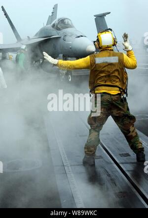 L'aviation de la marine américaine un maître de manœuvre dirige un F/A-18 Hornet en position pour lancer pendant les opérations de vol à bord du porte-avions Theodore Roosevelt (CVN 71) alors qu'en mer dans l'Océan Atlantique le 25 avril 2008. Banque D'Images