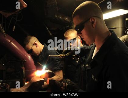 La Marine américaine, le Maître de 3e classe Chris Baker supervise comme pompier Kyle Gregory brazes un plafond pour un tuyau à bord du porte-avions USS Theodore Roosevelt (CVN 71) en cours dans le golfe d'Oman, le 7 janvier 2009. Banque D'Images