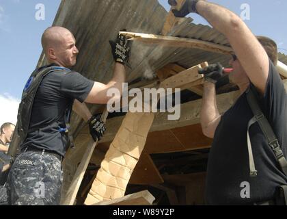 La Marine américaine Maître de 2e classe David Larson et le maître de Jeremy Fleming Réparer un toit endommagé sur un bâtiment sur l'île de la Gonâve, à Haïti, le 27 janvier 2010. Les marins, à partir de la station d'atterrissage amphibie USS Fort McHenry (LSD 43), participent à l'opération réponse unifiée. Ils fournissent l'appui militaire aux autorités civiles pour aider à stabiliser et améliorer la situation dans l'île. Banque D'Images