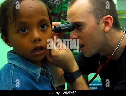 Le lieutenant de la Marine américaine Timothy Chinnock, un médecin affecté à la commande de transport maritime militaire navire-hôpital USNS Mercy (T-AH 19), examine une childís oreille pendant un programme d'action civique médicale dans Tidore, Indonésie, le 20 juillet 2010. La miséricorde est dans le Nord de la province des Moluques Indonésie mener Pacific Partnership 2010, le cinquième d'une série de missions de la Flotte du Pacifique américaine menée dans le cadre d'un exercice visant à renforcer les partenariats régionaux. Banque D'Images