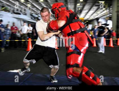 L'aviateur de la Marine américaine Kyle Babcock effectue une grève défensive après technique d'être enduites d'oléorésine de capsicum, également connu sous le nom de gaz poivré, à bord du porte-avions USS George Washington (CVN 73) actuellement en cours dans l'océan Pacifique le 26 septembre 2010. L'aérosol capsique donne l'expérience de formation des marins pour faire face aux situations qu'ils peuvent rencontrer dans le cadre de l'shipís la force de réaction de sécurité. Banque D'Images