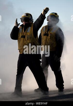 La Marine américaine Maître de 2e classe Jathan Lane (à gauche), directeur d'un avion affecté à V-1 de la Division du ministère de l'air à bord du porte-avions USS Carl Vinson (CVN 70), guides d'un aéronef sur une catapulte à vapeur en tant que maître de 3e classe David Myrtil observe en cours d'instruction actuellement en cours dans l'océan Pacifique le 1er décembre 2010. Le Carl Vinson et Carrier Air Wing 17 a effectué une formation de trois semaines de l'unité composite exercice avant un déploiement à l'ouest de l'océan Pacifique. Banque D'Images