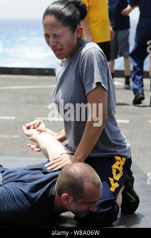 Maître de 2e classe Jaqueline Rodriguez soumet la simulation d'un suspect après avoir été aspergé d'oléorésine de capsicum, également connu sous le nom de gaz poivré, au cours de la formation en matière de sécurité à bord du navire de débarquement quai amphibie USS Comstock (LSD 45) dans le golfe d'Aden le 10 mai 2011. L Comstock est en cours des opérations de sécurité maritime et les efforts de coopération en matière de sécurité dans le théâtre dans la 5e Flotte des États-Unis zone de responsabilité. Banque D'Images