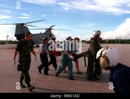 Un survivant de l'écrasement d'avion coréen est déplacé d'un hélicoptère d'évacuation à l'hôpital naval de la Marine par le personnel médical, l'équipage de vol et de bénévoles civils le Août 6, 1997. La Marine des États-Unis, U.S. Coast Guard, U.S. Air Force, et de nombreuses équipes de secours civils, actuellement à la recherche et sauvetage du vol KAL 801, a évacué les survivants de l'accident au cours de la matinée du 6 août. Banque D'Images