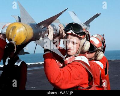 Ordnancemen Aviation charger un AIM-9 Sidewinder sur un F/A-18C Hornet à bord du porte-avions USS George Washington (CVN 73 comme le navire cuit dans le golfe Persique, le 19 février 1998. La bataille de Washington est groupe opérant dans le golfe Persique dans le cadre de l'opération Southern Watch qui est aux États-Unis et de la coalition de l'application de la zone d'exclusion aérienne au-dessus du sud de l'Iraq. Banque D'Images