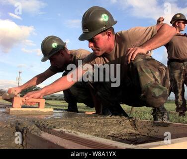 Des Seabees Mobile Naval Construction Battalion 7 ciment truelle comme ils pour parquet pour une personne de 500 tentes pour les travailleurs de secours à la base aérienne de Soto Cano, Honduras, le 10 novembre 1998. Plus de 1 000 membres du service des États-Unis contribuent à précipiter l'alimentation, le logement, l'eau pure, l'aide médicale et d'autres fournitures de secours à l'Amérique centrale sans abri par l'ouragan Mitch. Les Seabees sont déployés à partir de Roosevelt Roads, Puerto Rico et Gulfport, Mississippi Banque D'Images