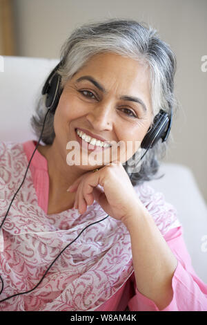 Senior woman listening to music on headphones Banque D'Images
