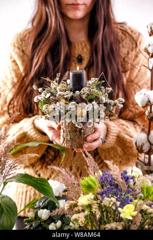 Fleurs séchées et des branches de saule dans les mains d'une fille. décorations, bougies, des branches de saule sec et une femme main sur l'arrière-plan. Le concept o Banque D'Images