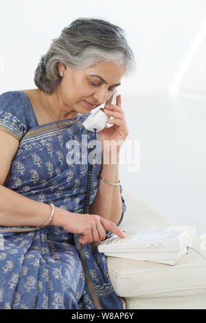 Senior woman dialing sur un téléphone fixe Banque D'Images