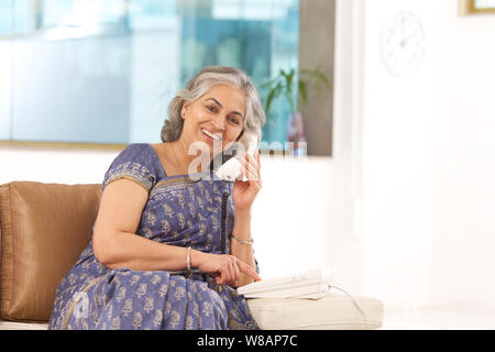 Senior woman dialing sur un téléphone fixe Banque D'Images