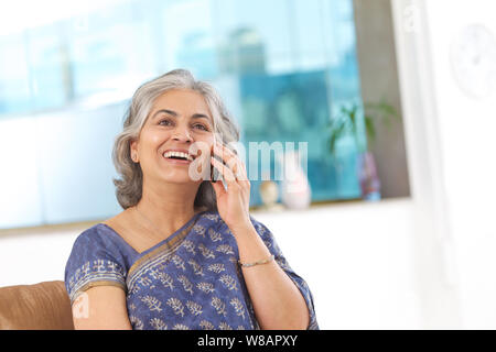 Une femme âgée commet des ragots sur un téléphone portable Banque D'Images