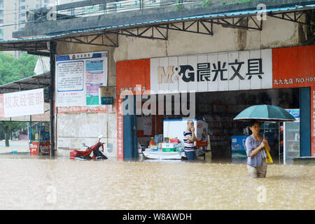 Un piéton marche sur une route inondée causées par de fortes pluies dans la ville de Jingdezhen, Chine de l'est la province de Jiangxi, du 19 juin 2016. 11 autres décès ont b Banque D'Images