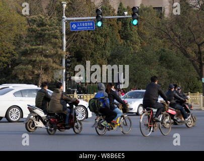 --FILE--Chinese cyclistes roulent à bicyclette ou de vélos électriques sur route, à Beijing, Chine, 7 avril 2016. Le nombre croissant de conducteurs de voiture privée est à l'o Banque D'Images