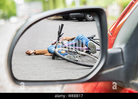 Cycliste homme inconscient allongé sur rue après accident de la scène à travers un miroir Side Car Banque D'Images