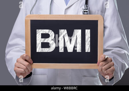 La mi-section de l'homme médecin montrant l'ardoise en bois avec Bmi Texte contre fond gris Banque D'Images