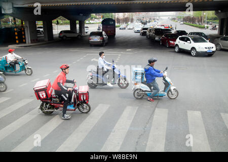 --FILE-delivermen- cuisine chinoise et d'autres cyclistes ride vélos électrique sur une route de Beijing, Chine, 13 avril 2016. Le nombre croissant de parking Banque D'Images
