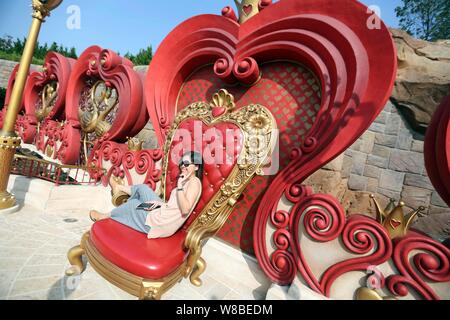 Un touriste pose pour des photos avec des installations du film 'Alice in Wonderland' dans le Disneyland de Shanghai au Shanghai Disney Resort à Pudong, Banque D'Images