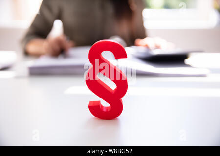 Close-up d'un symbole paragraphe rouge en face de personne travaillant sur le lieu de travail Banque D'Images