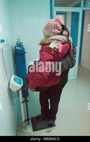 --FILE--fermier chinois Ma Xiaopeng porte son épouse paralysée Zhang Guilin pour mesurer son poids à un hôpital local de ville Mangshan, Luoyang city, c Banque D'Images