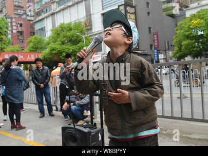 Garçon de neuf ans Ye Jianjun chante une chanson à quémander de l'argent sur une rue de la ville de Changsha, province de Hunan, en Chine centrale, 6 avril 2016. Un jeune Chine Banque D'Images