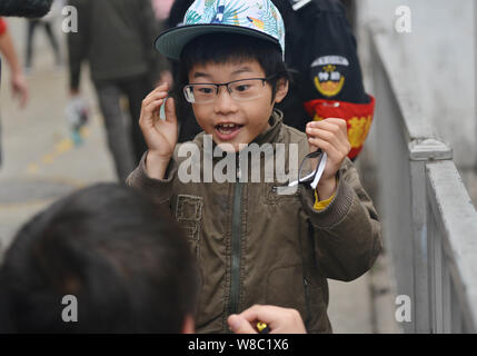 Garçon de neuf ans Ye Jianjun réagit alors qu'il tente sur une paire de lunettes d'un journaliste lors d'une pause de sa performance dans une rue de la ville de Changsha, c Banque D'Images