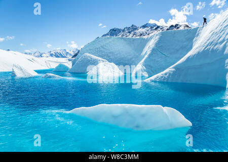 La glace blanche ressemblant à de grands bâtons d'icebergs d'un bleu profond sur le lac Glacier Matanuska. Ci-dessus, un guide d'escalade sur glace Les champs d'une ligne pour abaisser un c Banque D'Images