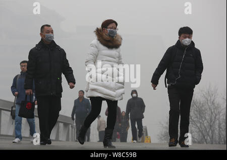 --FILE--piétons, la plupart d'entre eux porter des masques, à pied dans une rue de smog lourde à Beijing, Chine, 25 décembre 2015. Les habitants de Beijing ont acheté plus de Banque D'Images