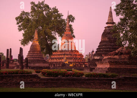 Trois stupas sur les ruines d'un temple bouddhiste Wat Mahathat au crépuscule du soir. Parc historique de Sukhothai. Thaïlande Banque D'Images