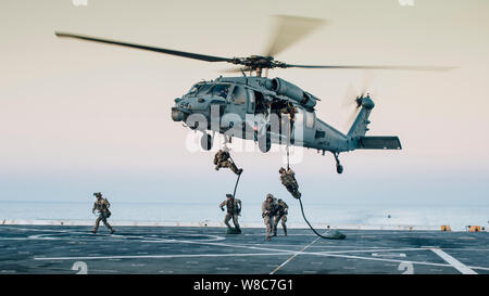 190726-M-HB658-1033 Golfe Arabique (26 juillet 2019) Les gardes côte avec l'équipe d'intervention de la sécurité maritime, l'interdiction du détachement avancé de l'équipe 1, sur la corde rapide quai de transport amphibie USS John P. Murtha (LPD 26) d'une Sea Hawk MH-60S avec l'Escadron d'hélicoptères de combat de la mer 26 au cours d'un exercice d'entraînement. Le boxeur groupe amphibie et la 11e unité expéditionnaire de marines sont déployés dans le domaine de la 5e flotte américaine des opérations à l'appui des opérations navales pour assurer la stabilité et la sécurité maritime dans la région Centrale, reliant la Méditerranée et le Pacifique par l'EMTE Banque D'Images
