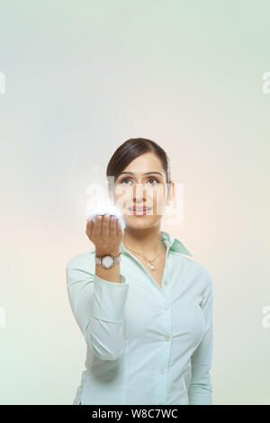 Femme d'affaires utilisant un smartphone et des lumières en streaming à partir de lui Banque D'Images