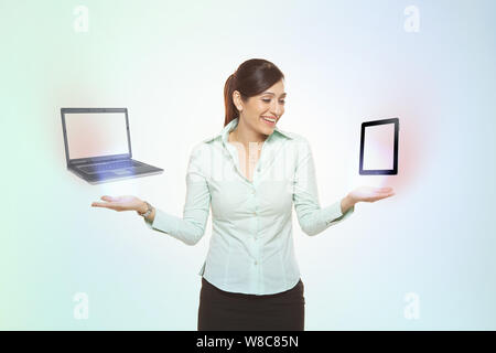 Femme d'affaires comparant un PC portable à une tablette numérique Banque D'Images