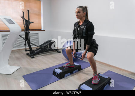 Les jeunes ATHLETIC Athletic Girl doing squats avec poids en fonction EMS Banque D'Images