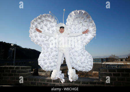 L'artiste chinois Kong Ning, droit, vêtu d'un costume de papillon fait avec 365 masque de visage pose à la Grande Muraille de Badaling, à la périphérie de Beijing, Banque D'Images