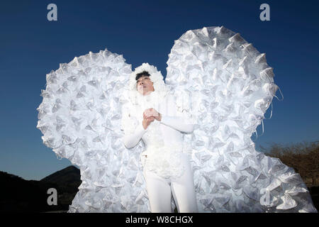 L'artiste chinois Kong Ning, droit, vêtu d'un costume de papillon fait avec 365 masque de visage pose à la Grande Muraille de Badaling, à la périphérie de Beijing, Banque D'Images